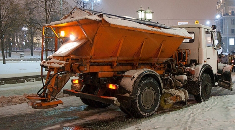 A snow plow spreads salt to melt ice on the road. (click for credit)